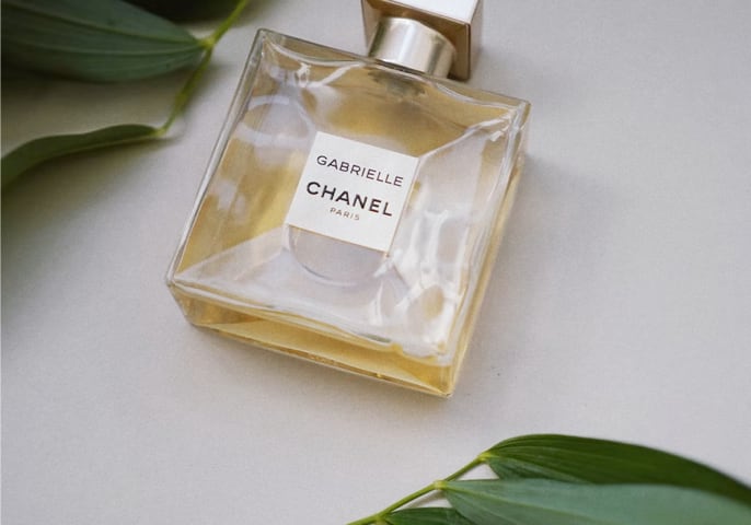 perfume laying on a table with leaves surrounding